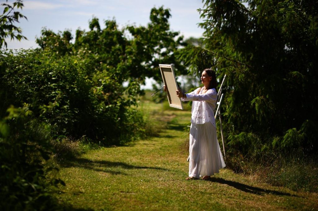 Elena Wuest with a painting in the garden